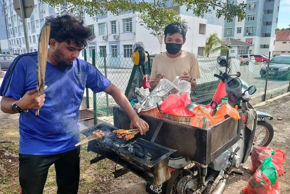 阿斯拉沙烈（右起）与亲戚开著摩哆，在住宅花园流动式售卖沙爹。