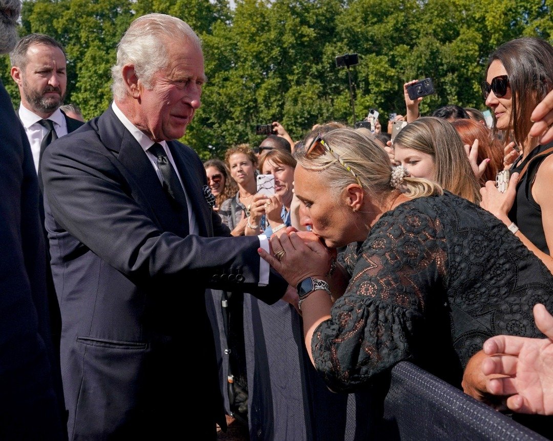 查尔斯三世和妻子卡米拉王后周五在伦敦白金汉宫前，花了10多分钟向前来悼念女王的民众亲切互动、握手。有一名妇女热情吻了他的手。（图取自路透社）