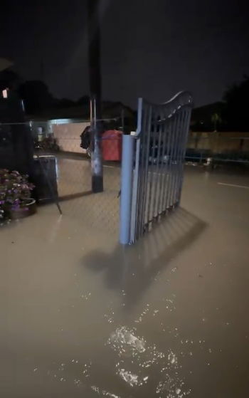 暴雨引发的水灾已使家外水位淹至膝盖，马路完全被淹没，居民出行受阻。