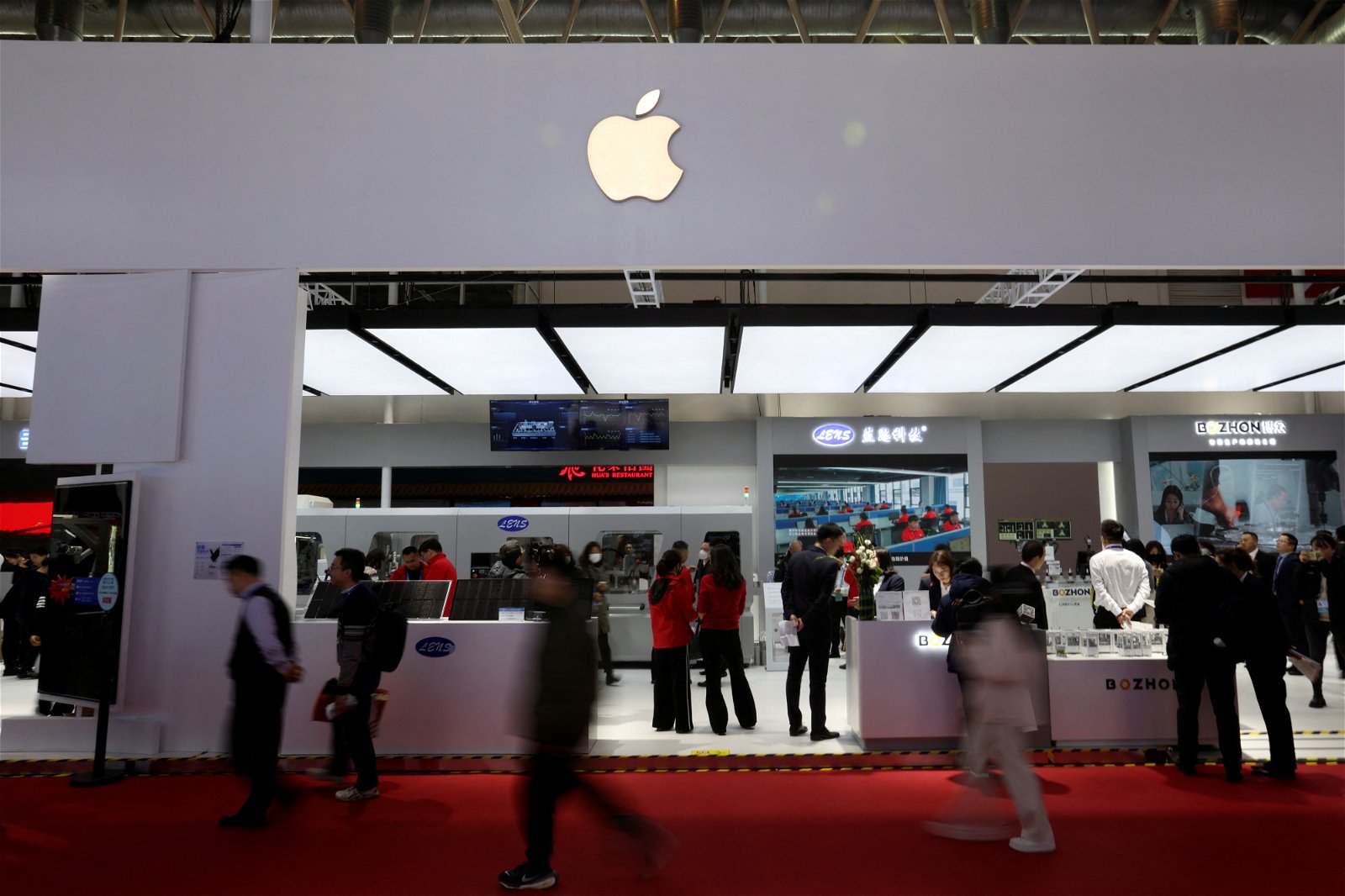 在中国链博会，人们走过展示着苹果标志的苹果供应商展位。（图取自路透社）