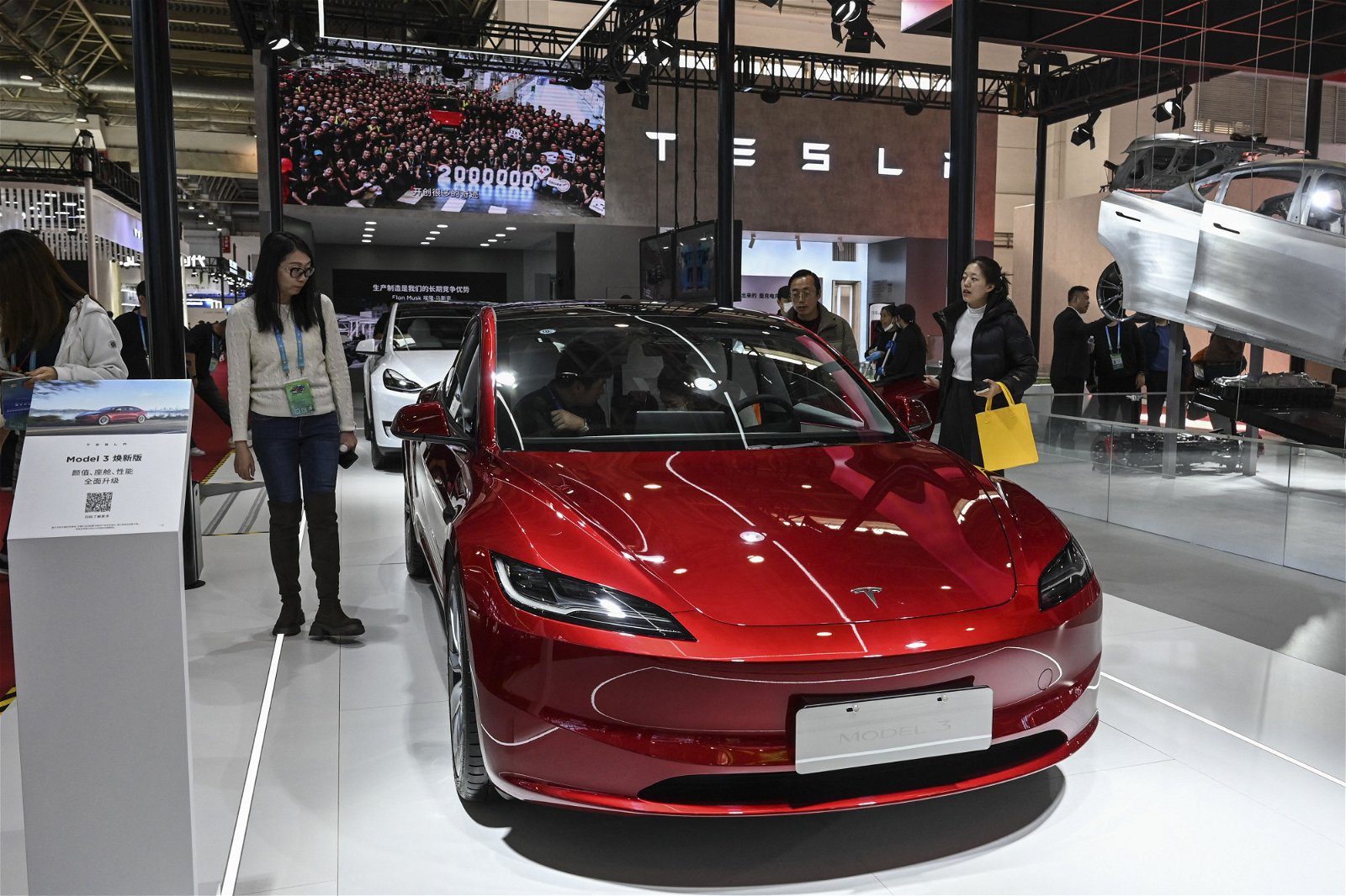 周五在北京举行的首届中国国际供应链博览会（CISCE）期间，人们在特斯拉展位上试用特斯拉电动车Model 3。（图取自法新社）