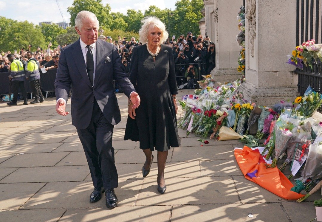 查尔斯三世和妻子卡米拉王后在伦敦白金汉宫前观看民众自发献上的鲜花。（图取自路透社）