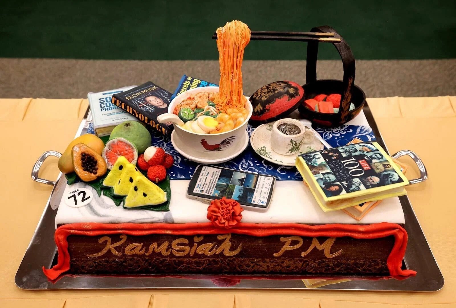 献给李显龙的蛋糕以当地美食、水果、书籍等物品为造型，写上“Kamsiah”（感谢）总理的祝语。